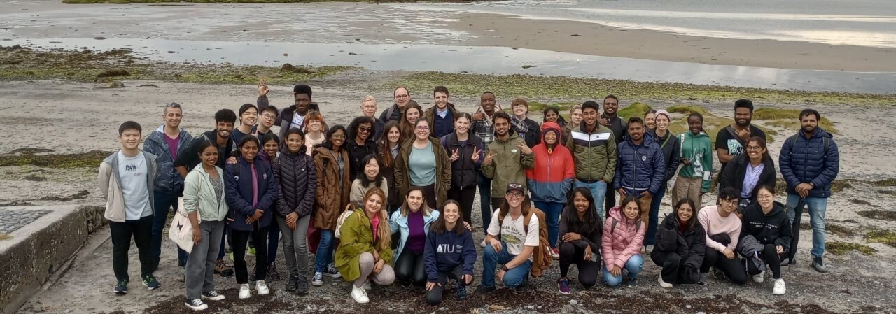 Group of diverse International Student Society members smiling on a beach outing, hero image for the website.
